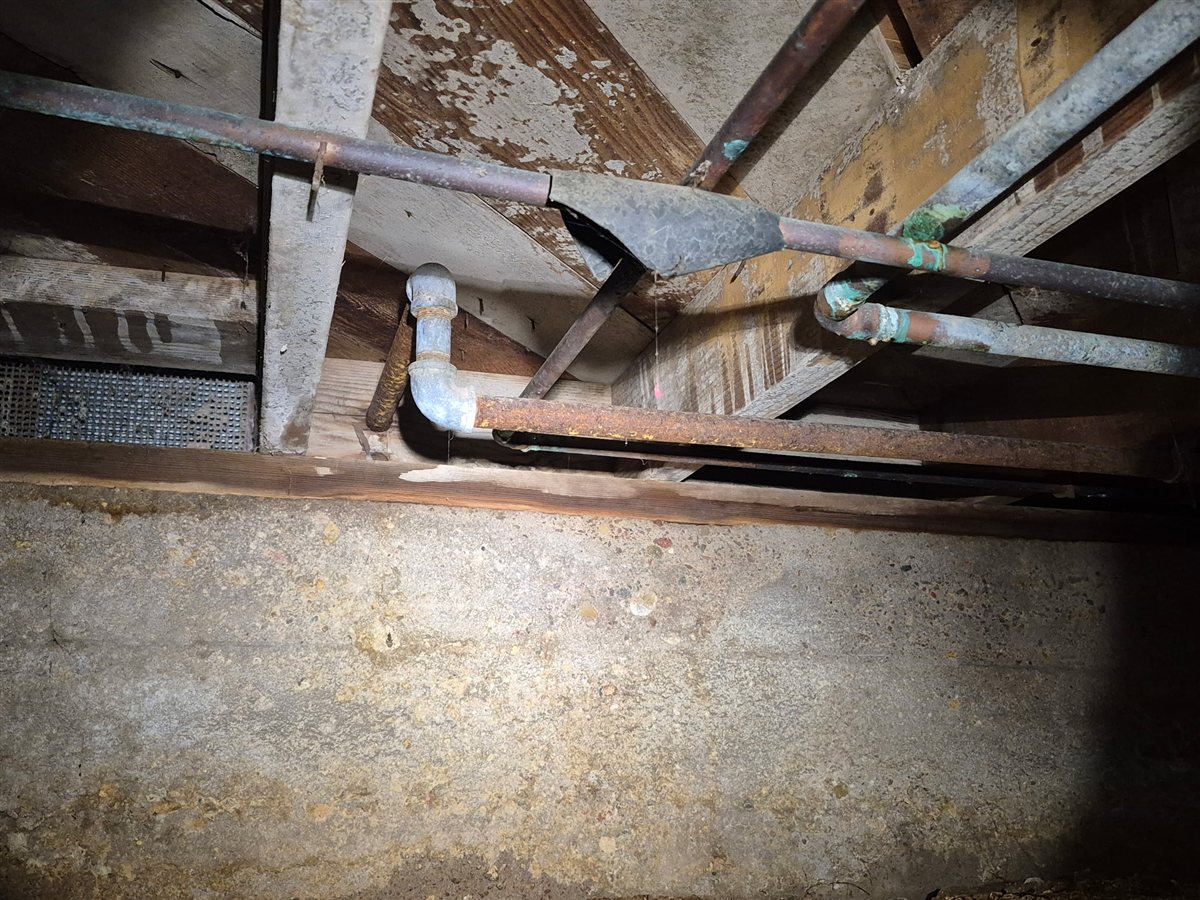 Old galvanized supply lines under a house.