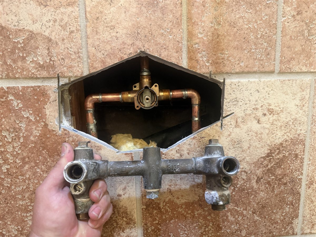 Old shower valve body removed with the new valve installed.