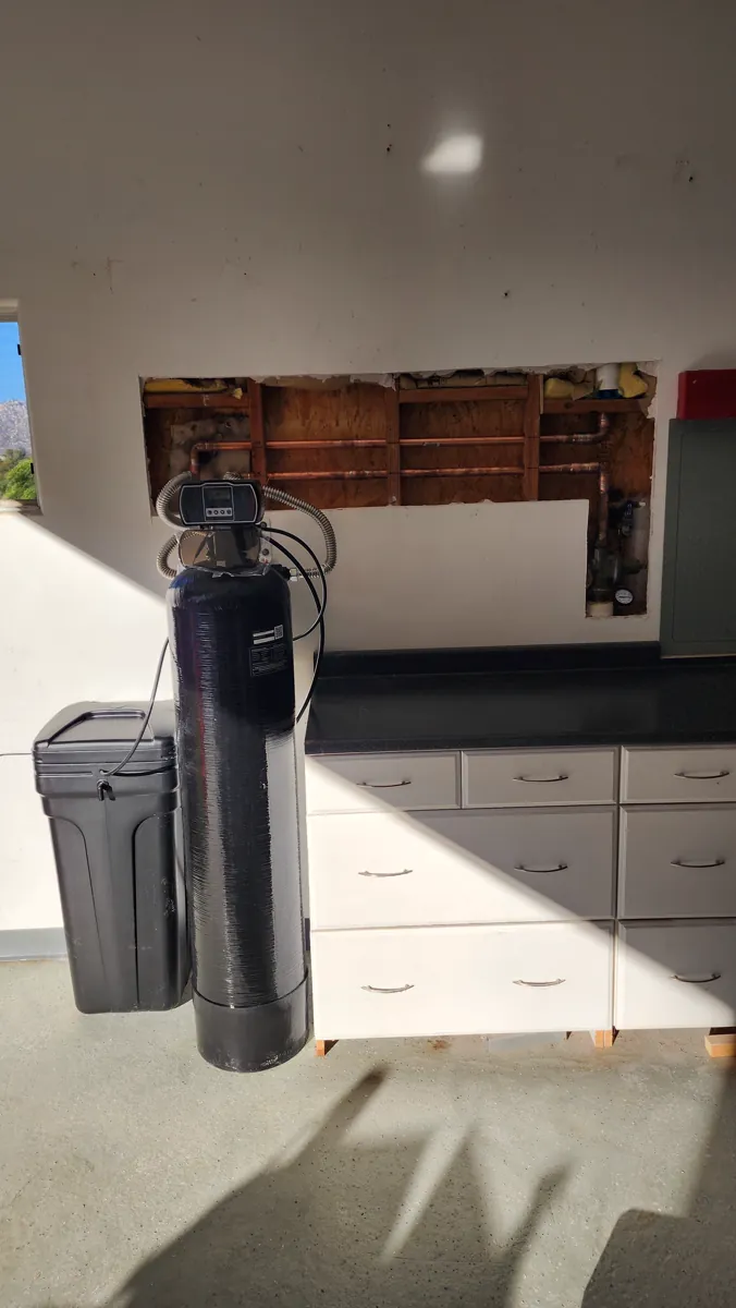 Water softener and brine tank beside a new copper manifold.