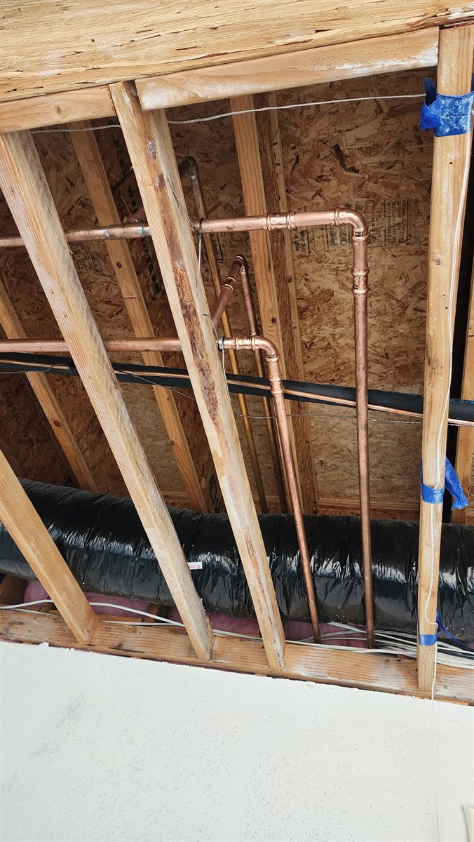 New water lines run through open framing during a repipe.
